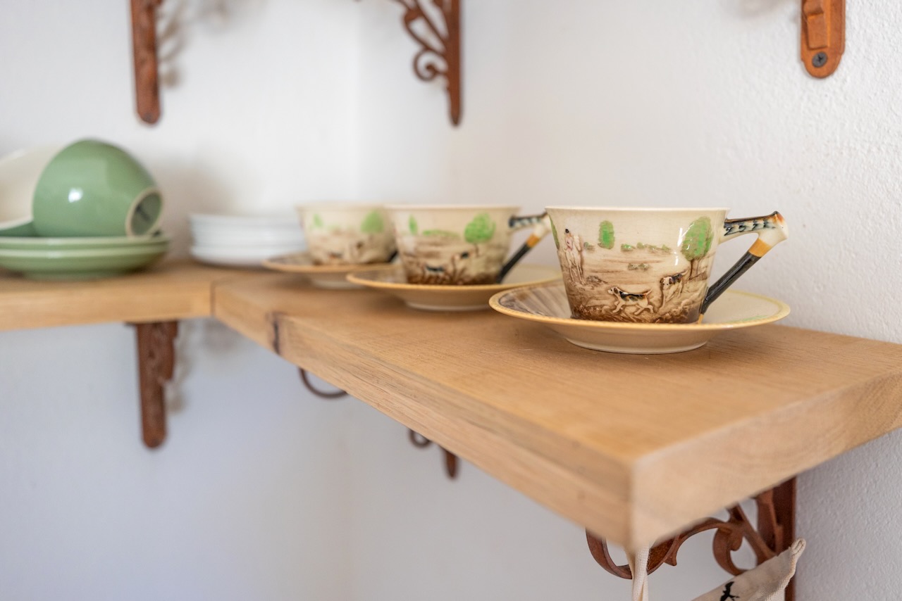 Elegant tea service with fine china cups and saucers on wooden shelving